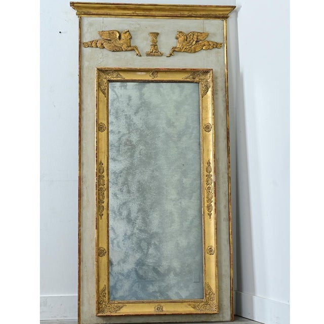 A large 19th-century French Empire-style trumeau mirror that is bold yet refined. Its frame is topped with a gold-gilt...