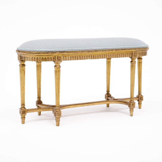 The generous oval upholstered seat rests above a finely carved gilt wood frame with a classic fluted frieze. Six slender...