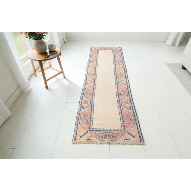 This is a vintage Turkish Oushak rug from the Mid 20th Century. The piece was hand-knotted.