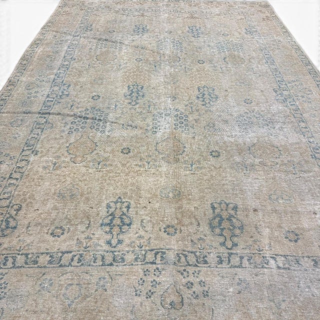 This antique Tabriz rug features a delicate allover composition of minute floral patterns set against a soft ivory ground....