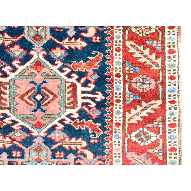 An exquisite antique Persian Heriz rug from the 1920s, hand-woven with high-quality wool and natural dyes. This piece...