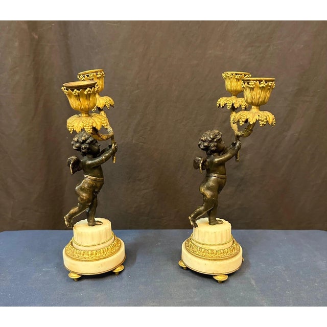 This vintage pair of late 19th century Continental bronze & marble candelabra is decorated with dark patinated cherubs....