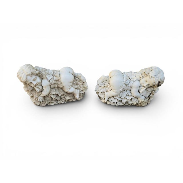 Charming pair of marble sculptures depicting two cherubs surrounded by finely carved foliage. Crafted in Italy during the...