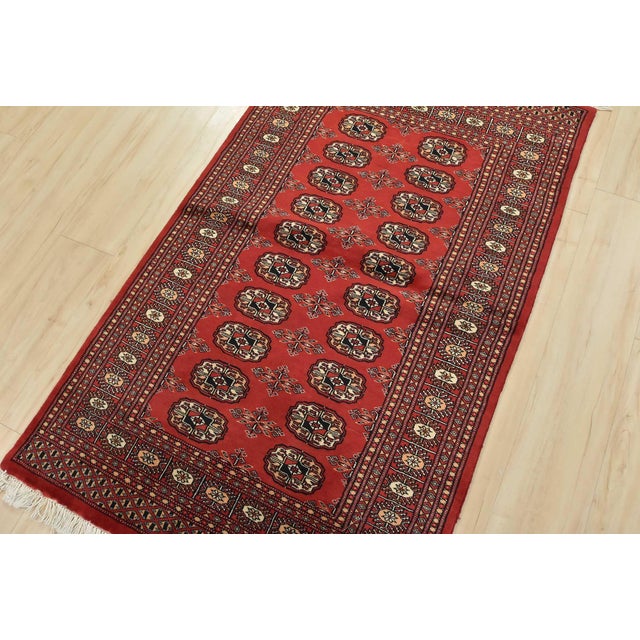 A tribal Bokhara rug hand-knotted with an all-wool pile on a cotton foundation. This finely woven oriental rug features...