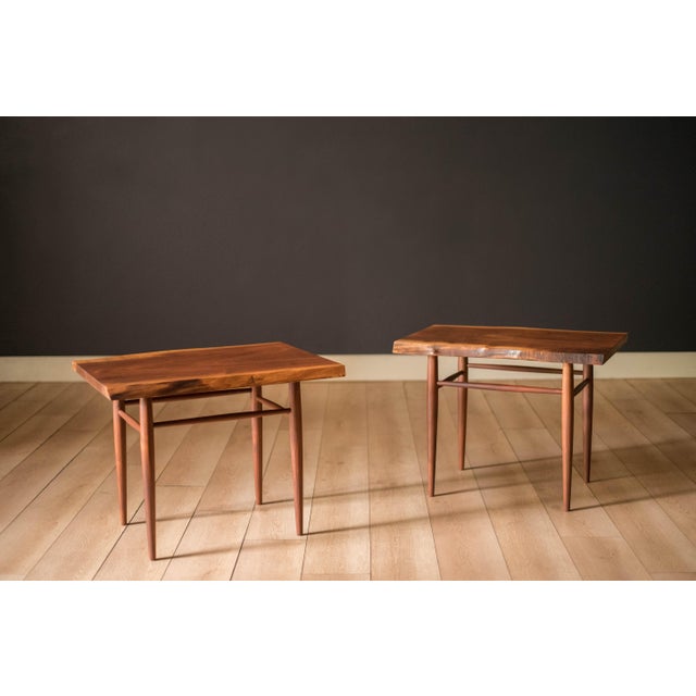 Vintage pair of side tables in solid walnut handcrafted by George Nakashima, circa 1971. This custom set features a free...