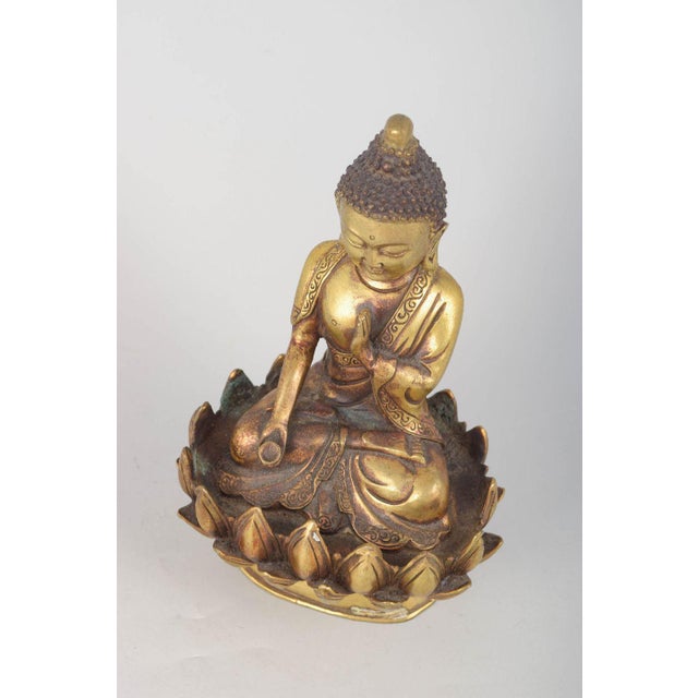 Gilt bronze Buddha figure. Seated Buddha figure executed in gilt bronze with one hand raised in a symbolic gesture and...