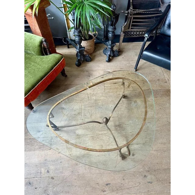 A large gold gilt wrought iron three legged coffee table by Maison Ramsay. The scrolled console legs with sweeping...