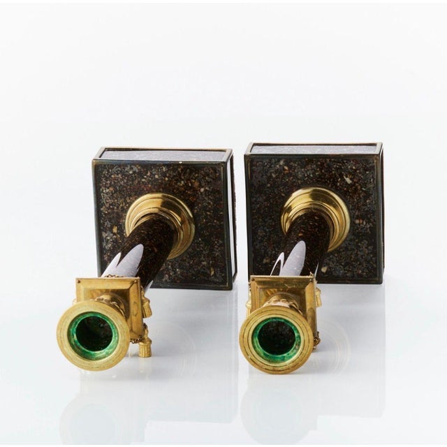 The pair of reverse glass faux porphyry candlesticks with brass mounts (lacking one tassel)