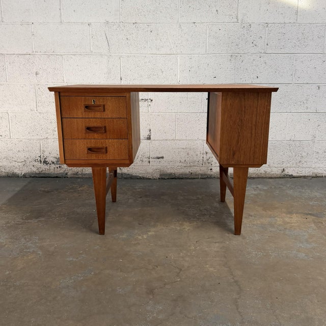 A compact Danish teak writing desk from the 1960s with an especially useful arrangement of storage built into the form....