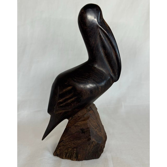 Vintage carved dark wood pelican figurine. The wood surface of the pelican has a very smooth satin texture; the...