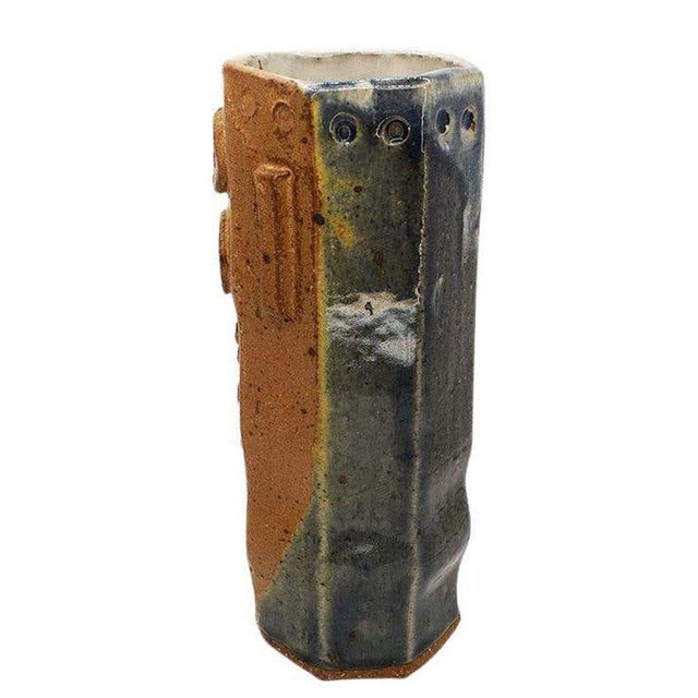 Glazed in an ombre blue, cream, and brown, this tall geometric vase will bring a touch of mid-century to any space. The...