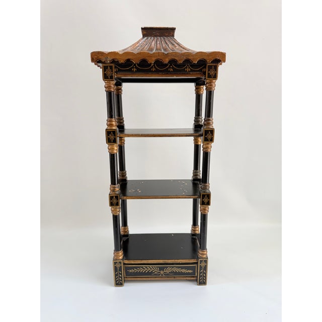 Vintage Chinoiserie pagoda wall shelf constructed of black lacquer wood with painted gold gilt detailing. Features a...