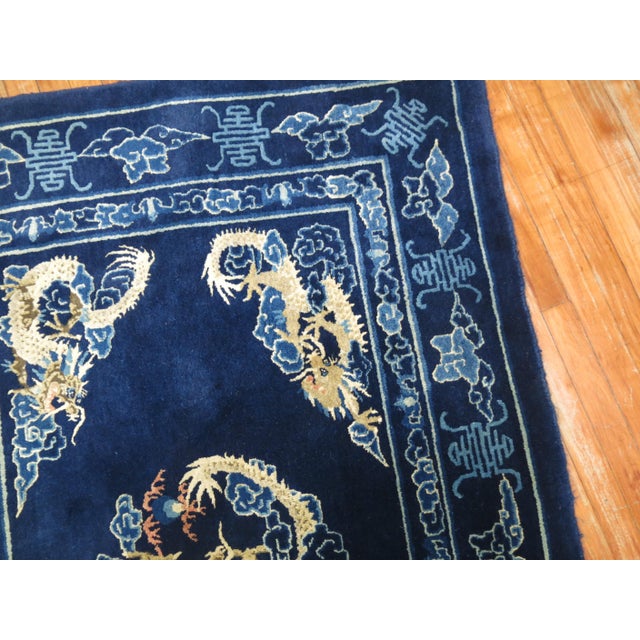 A full pile 20th century Chinese rug with 4 dragons floating on a navy blue ground. Measures: 4'1" x 6'1".