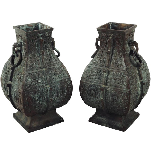 An impressive pair of large heavy cast bronze urns, with bold relief designs as well as more dimensional elements running...