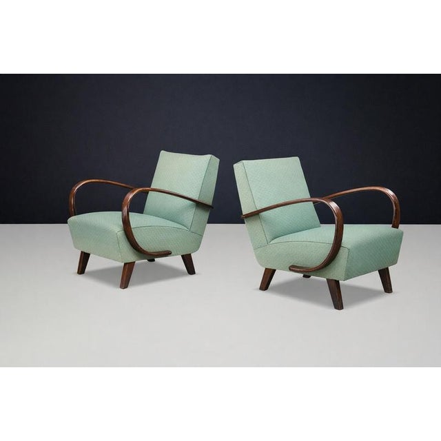 Sculptural Art Deco lounge chairs by Jindřich Halabala, featuring elegant bentwood armrests and original upholstery; a...
