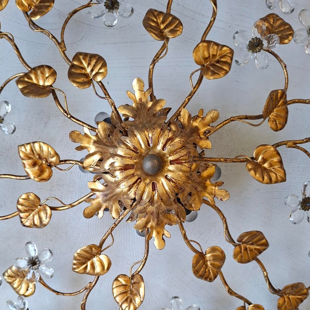 This gilt metal metal ceiling lamp with a diameter of 75 cm features branches with leaves and crystal flowers and has 8...