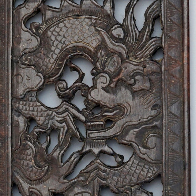 A heavy dark soapstone rectangular panel that is carved with a four- clawed dragon flying in the clouds over sea waves and...