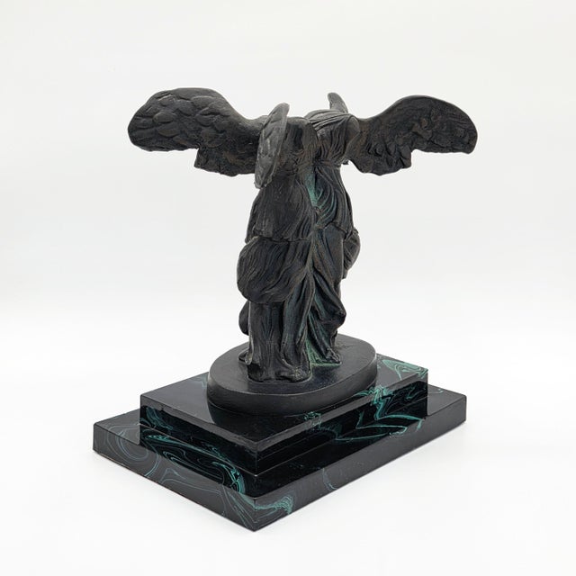 A striking Dalí resin sculpture depicting Two Nikes / La Double Victoire de Samothrace, presented on a contrasting marble...