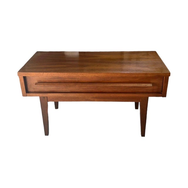 This vintage mid-century modern end table or stand features a compact rectangular wood case with a single full-width...