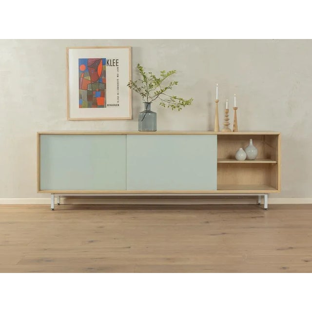 Wonderful sideboard from the 1960s. Corpus in a bleached walnut veneer with three glass sliding doors in cream white,...