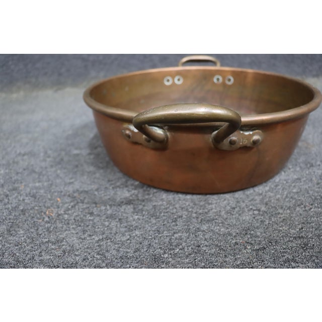 Antique solid copper jam pan featuring a wide, shallow form with riveted brass side handles. Traditionally used for making...