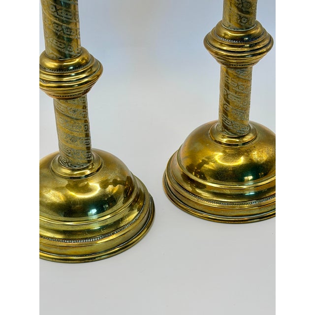 Elegant pair of vintage brass-plated metal candlesticks featuring finely etched column details and warm aged brass tones....
