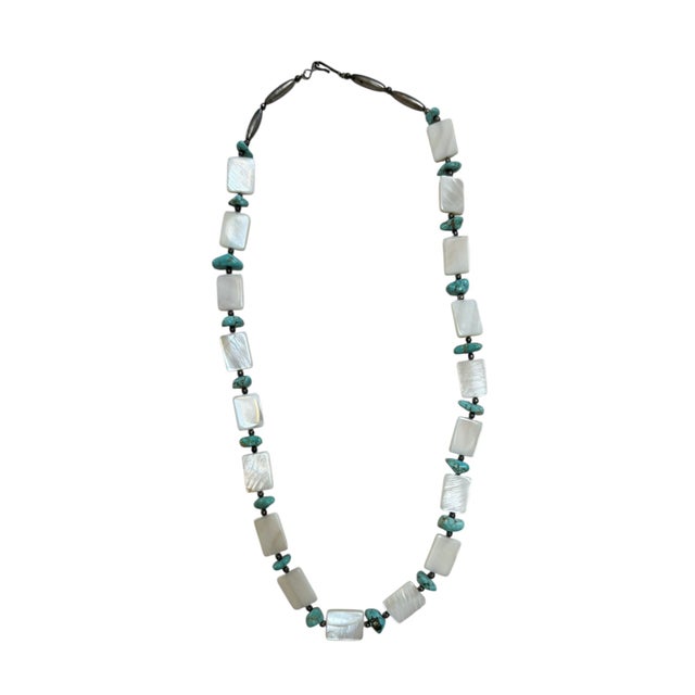 This necklace features polished, rectangular white shell beads interspersed with irregularly shaped turquoise nuggets and...