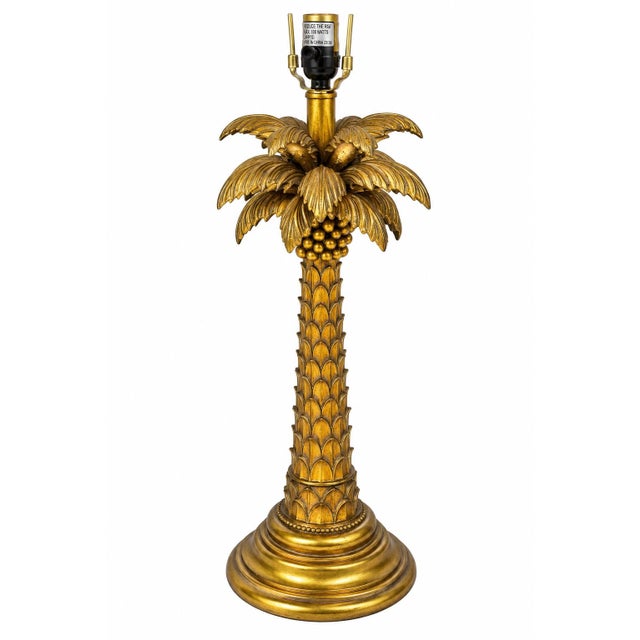 A stunning vintage Hollywood Regency table lamp featuring an ornate gilt palm tree design with beautifully detailed...