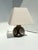 A striking ceramic table lamp with a dark brown glaze and a spiral glaze decoration. The compact, spherical body extends...