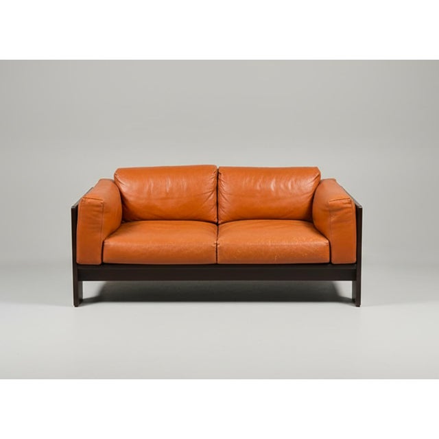 A two-seater sofa designed by Tobia Scarpa for Gavina, the rosewood frame holds cognac-colored leather cushions. The frame...