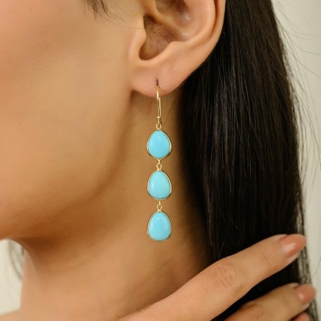 These elegant drop dangle earrings showcase three natural turquoise cabochons totaling 11.2 carats, arranged in a 14k...