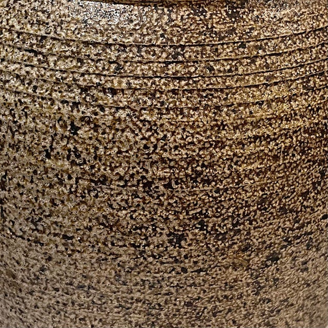 1970's hand-crafted stoneware studio pottery jar with lid. The ridged body and lid feature a textured brown and black salt...