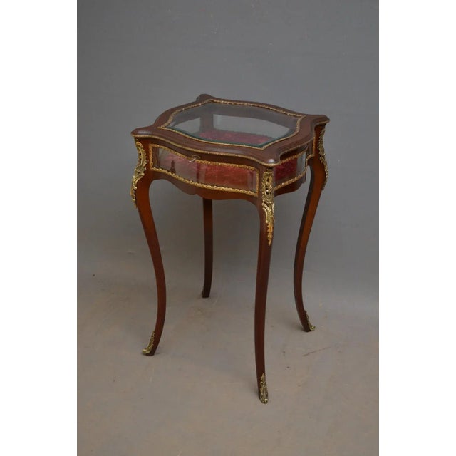 Edwardian mahogany display table of shaped outline, having hinged lid with bevelled edge glass and original working lock...