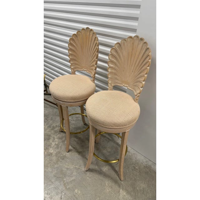 A striking pair of vintage bar stools featuring sculptural shell-inspired backs and gently curved legs. The carved frames...