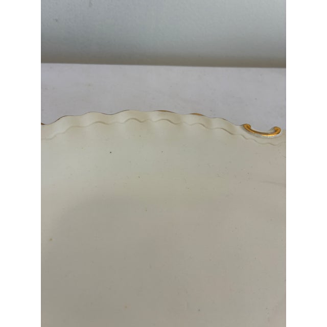Vintage oval serving platter featuring a classic white / ivory finish with decorative gold trim and a scalloped edge...