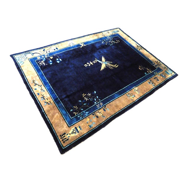 Blue field displaying a flying phoenix. All corners decorated with botanical motifs. Wool pile on cotton foundation. Hand...
