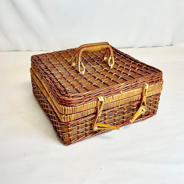 This is a lovely darker stained wicker suitcase style basket. It has a two-rattan clasp closure and rattan wrapped handles...