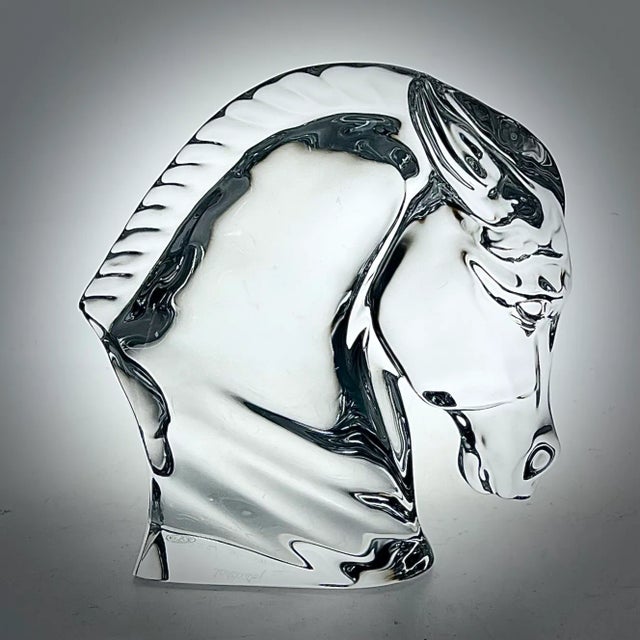 A Baccarat clear crystal sculpture depicting a horse head designed by Tauni De Lesseps. This striking piece features...