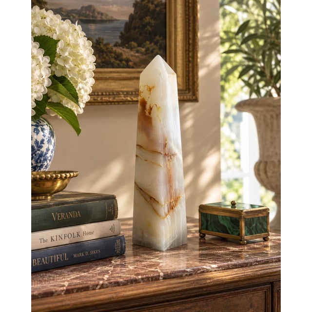 A beautifully proportioned onyx marble obelisk in richly veined shades of green, cream, and brown. The sculptural...