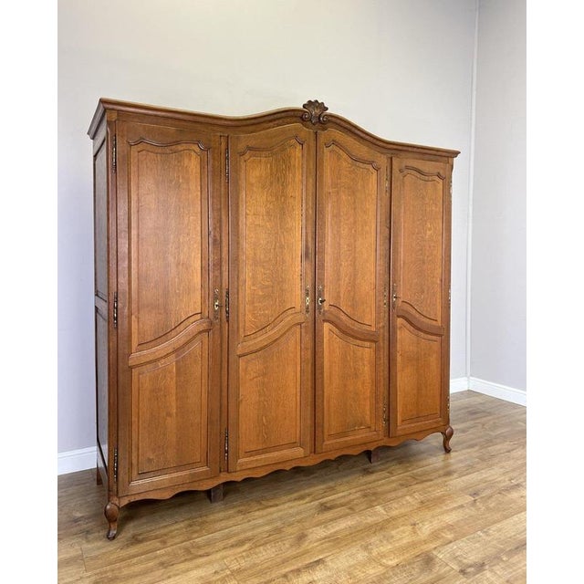 An elegant Vintage French Louis wardrobe in oak, featuring four beautifully panelled doors, a sweeping shaped top with...