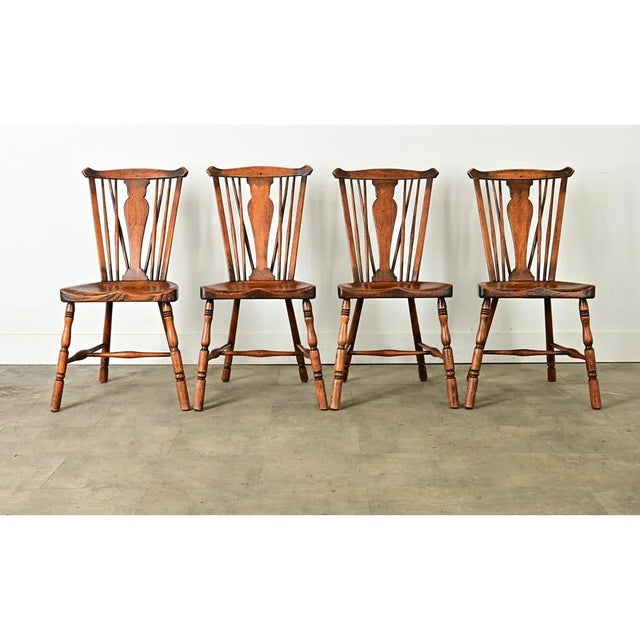 A charming set of four, circa 1890 English Windsor chairs made from oak with oxbow handrails at the top, connecting to...