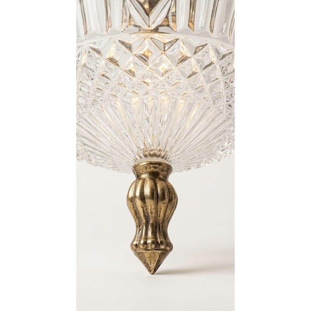 A striking vintage pendant light featuring a beautifully textured glass shade topped with an elegant brass fitting. The...