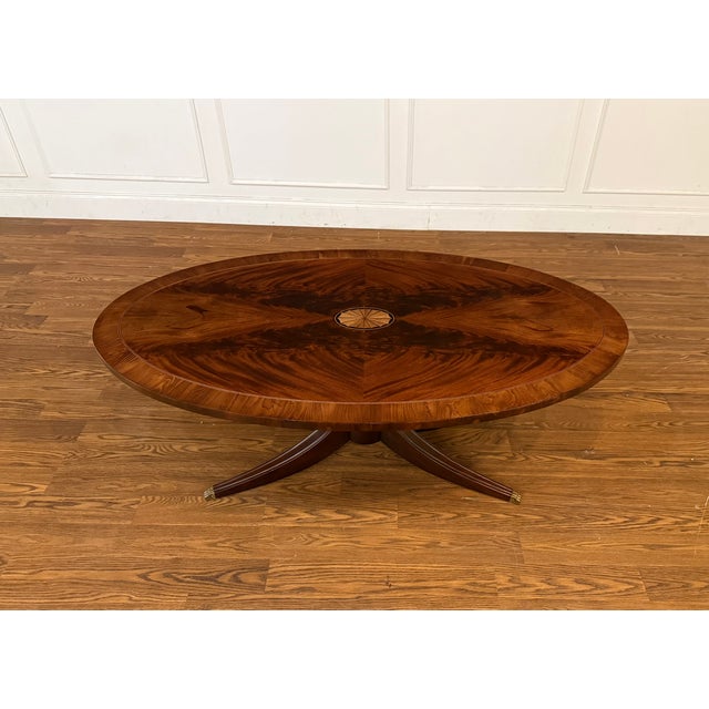 This oval coffee table features a booked-and-butted crotch mahogany top with a yew wood border and a medallion in the...