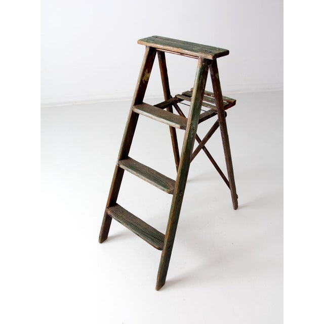 This vintage three-step wood folding ladder dates back to the early to mid-20th century. The green painted finish has...