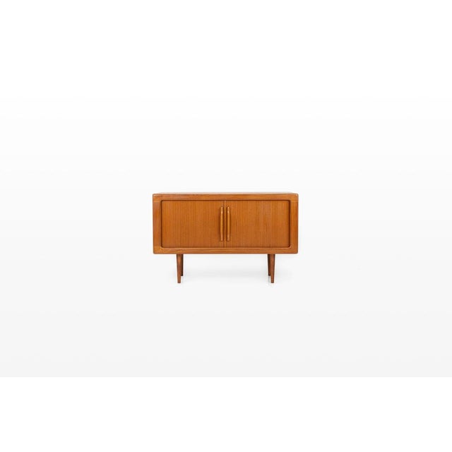 Authentic Danish sideboard from the 1960s, made in richly grained teak wood. This vintage piece features smooth tambour...