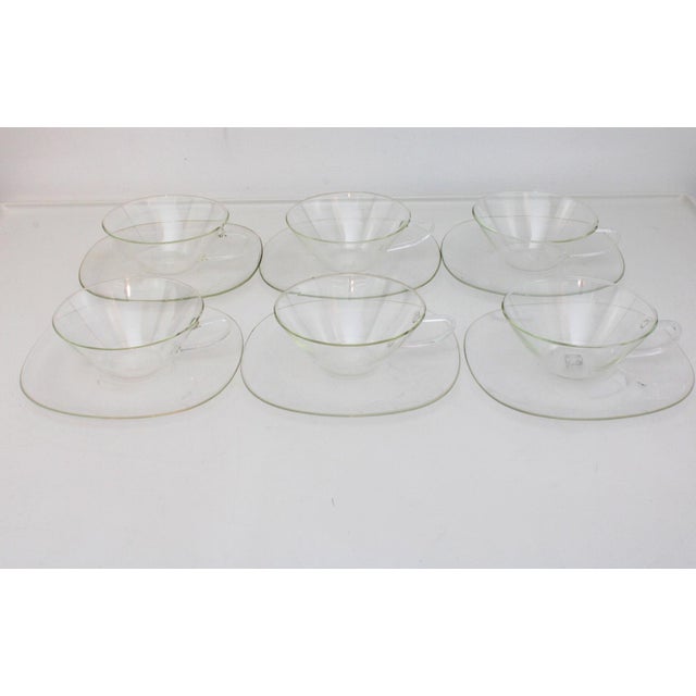 6 teacups with saucers, made of fireproof glass, plus a small handle jug for milk or lemon This piece has an attribution...