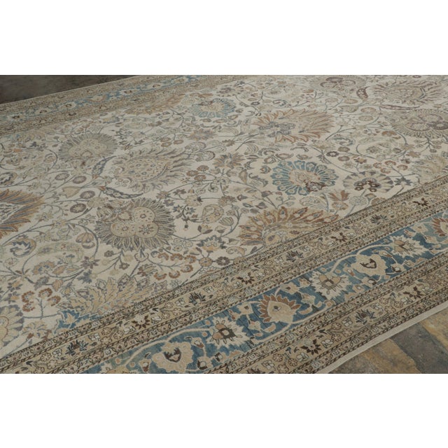 Hand-knotted in wool and originating circa 1900-1920, this 11x18 distressed antique Persian Mashad rug is an exceptional...