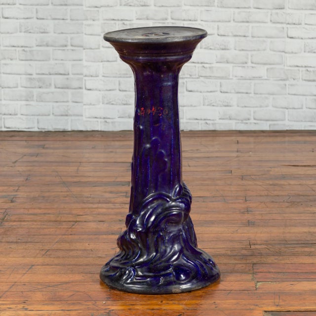 A Chinese antique dark blue glazed pedestal stand with raised motifs. Boasting a lovely dark blue glazed patina, this...
