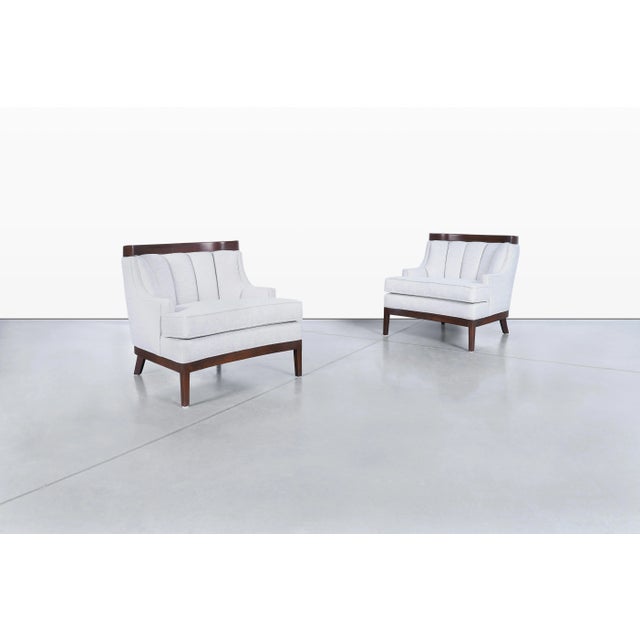 Beautifully sculpted and elegantly detailed, this pair of vintage walnut lounge chairs captures the cultivated character...