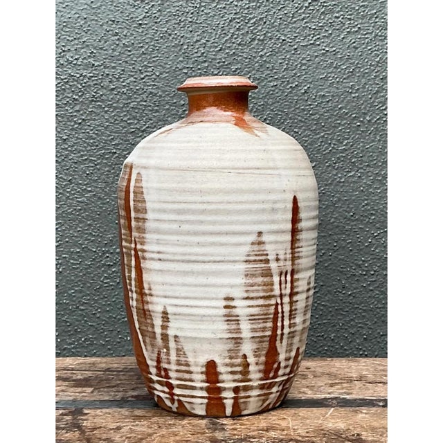 This vintage abstract ceramic vessel showcases a classic bottle form with a gently tapering shoulder and a subtly flared...